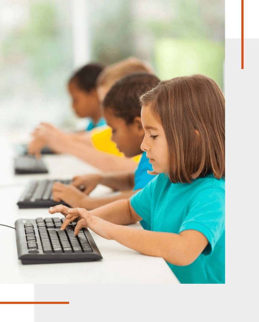 Children typing on keyboards in a classroom.