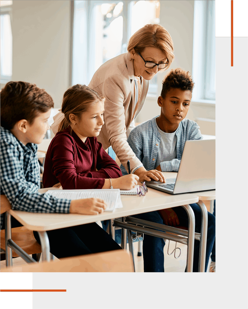 Teacher helping students with a laptop in a classroom.