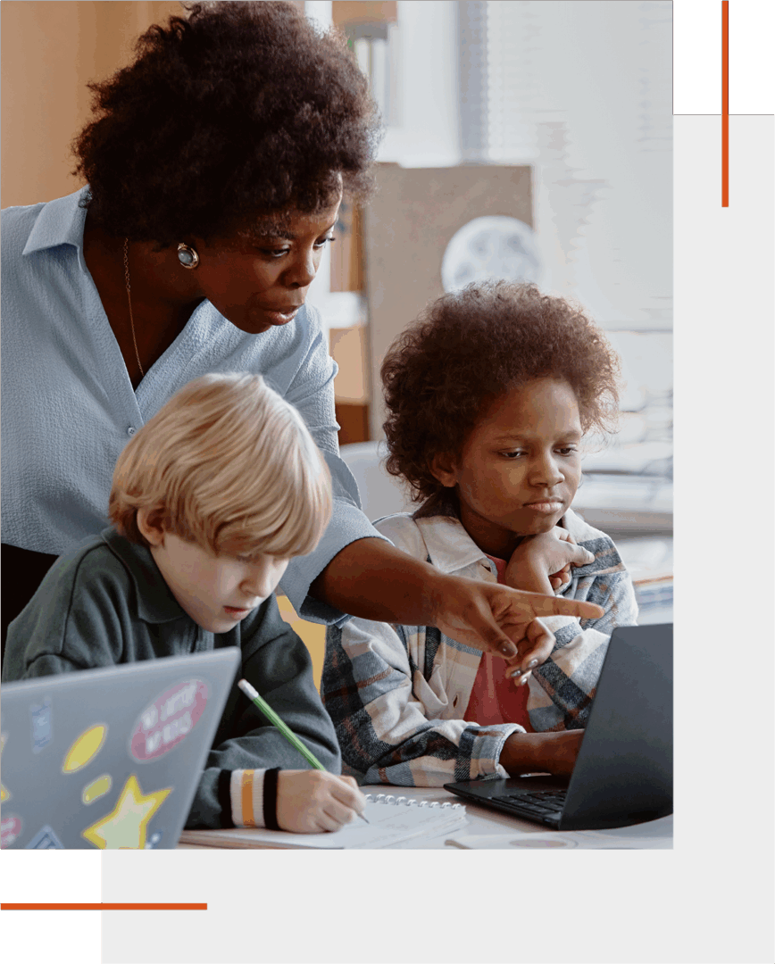 Teacher helping two young students with a laptop.