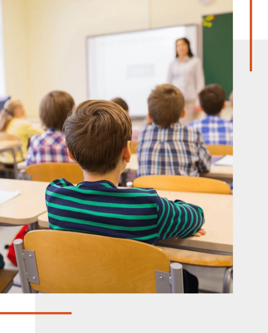 Children sitting in a classroom, teacher instructing.