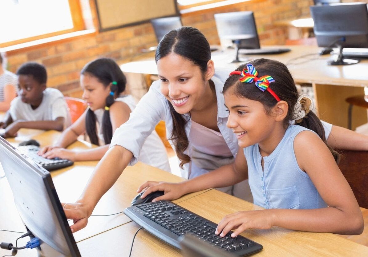 Teacher and students using computers in classroom.